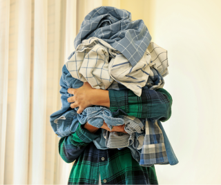 person holding a pile a clothes